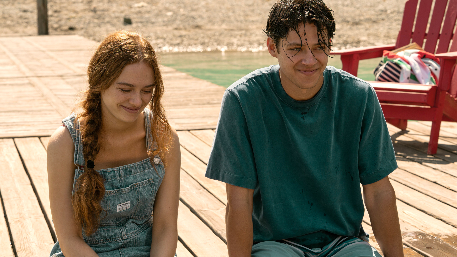 Two teenagers (Sadie Soverall as Percy Fraser, Matt Cornett as Sam Florek) sitting on a a wooden dock over a lake, in 'Every Year After.'