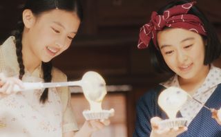 Two Japanese girls fill small tart cases with filling, in the Netflix show 'The Makanai: Cooking for the Maiko House.'