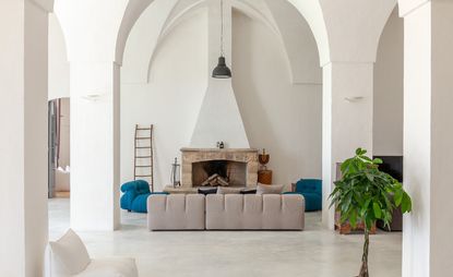 Lounge space featuring a stone fireplace, blue and beige seating and high, white domed ceiling