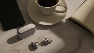 Technics EAH-AZ100 earbuds on table with coffee and book