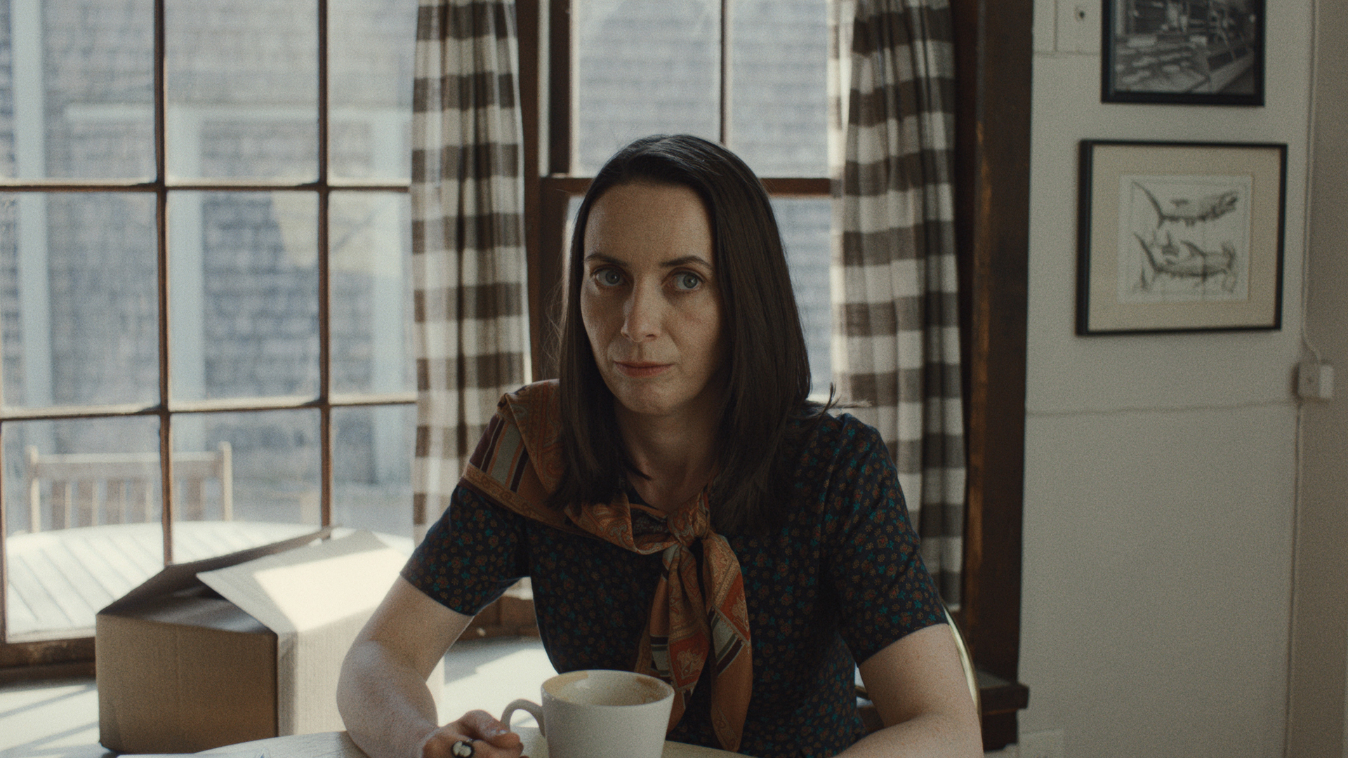 Patricia sitting at a table with a cup in front of her in Widow's Bay