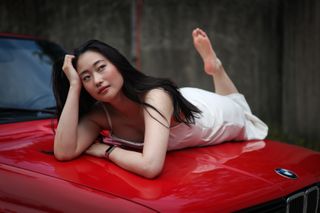 Canon EOS R5 Mark II sample image: a female model lying on the bonnet of a classic red BMW