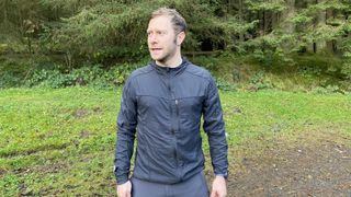 A man in open woodland wearing the Nathan Stealth Jacket