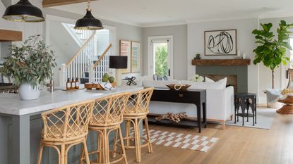 A modern farmhouse-style, open-plan kitchen and dining area with bamboo bar stools and white sofa