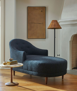 blue chaise lounge in a room with a small table and floor lamp