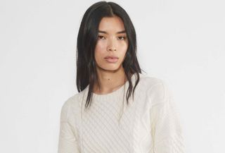 Aritzia model wearing cropped cableknit sweater.