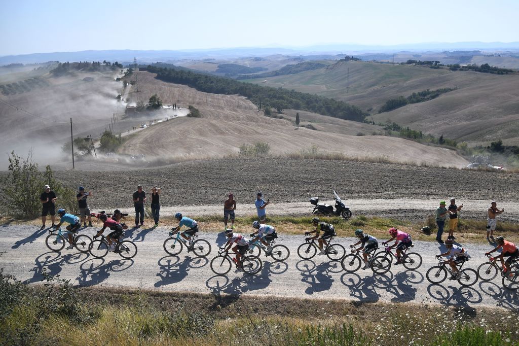 The pack of riders pedal through a dusty gravel road in the oneday classic cycling race Strade Bianche White Roads on August 1 2020 around Siena Tuscany Photo by Marco Bertorello AFP Photo by MARCO BERTORELLOAFP via Getty Images
