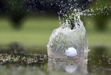 Golf ball landing in pond, close-up, symbolizing landing in a trap or snafu.