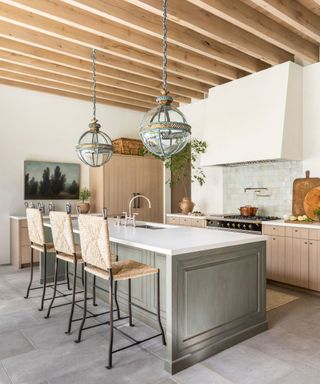 white kitchen with wood ceiling beams and large rustic pendant lights