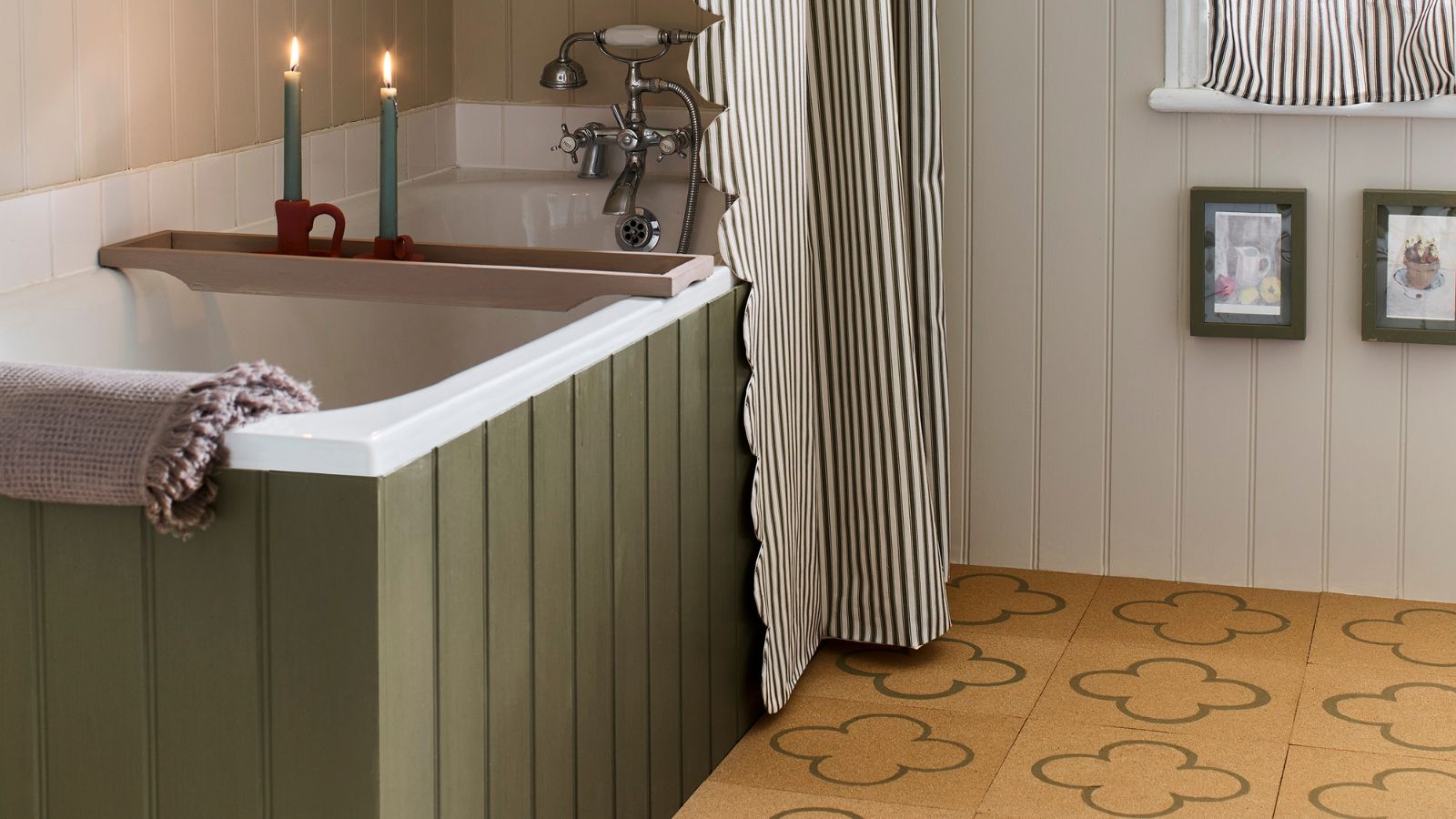 A painted green sided bath with a green striped shower curtain. In a bathroom with a yellow tile floor and white shiplap walls. 