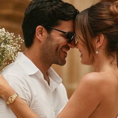 A couple on their wedding day featuring a woman wearing a gold Bulova watch and holding a bouquet of white flowers