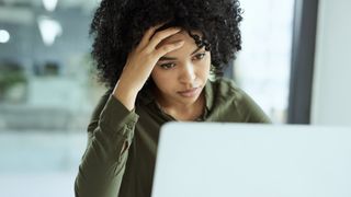 A woman looking stressed and unhappy while using a laptop