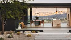 desert modernist landscaping design with rocks, gravel, plants and pavers, with a pergola and outdoor kitchen, and view to mountains beyond