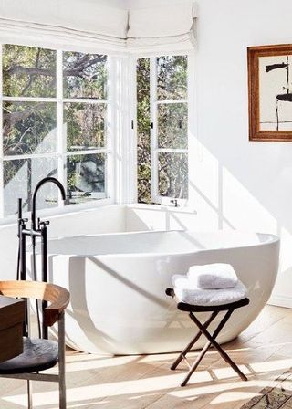 Farmhouse bathroom with standalone white tub and black matte faucets, alongside modern furniture