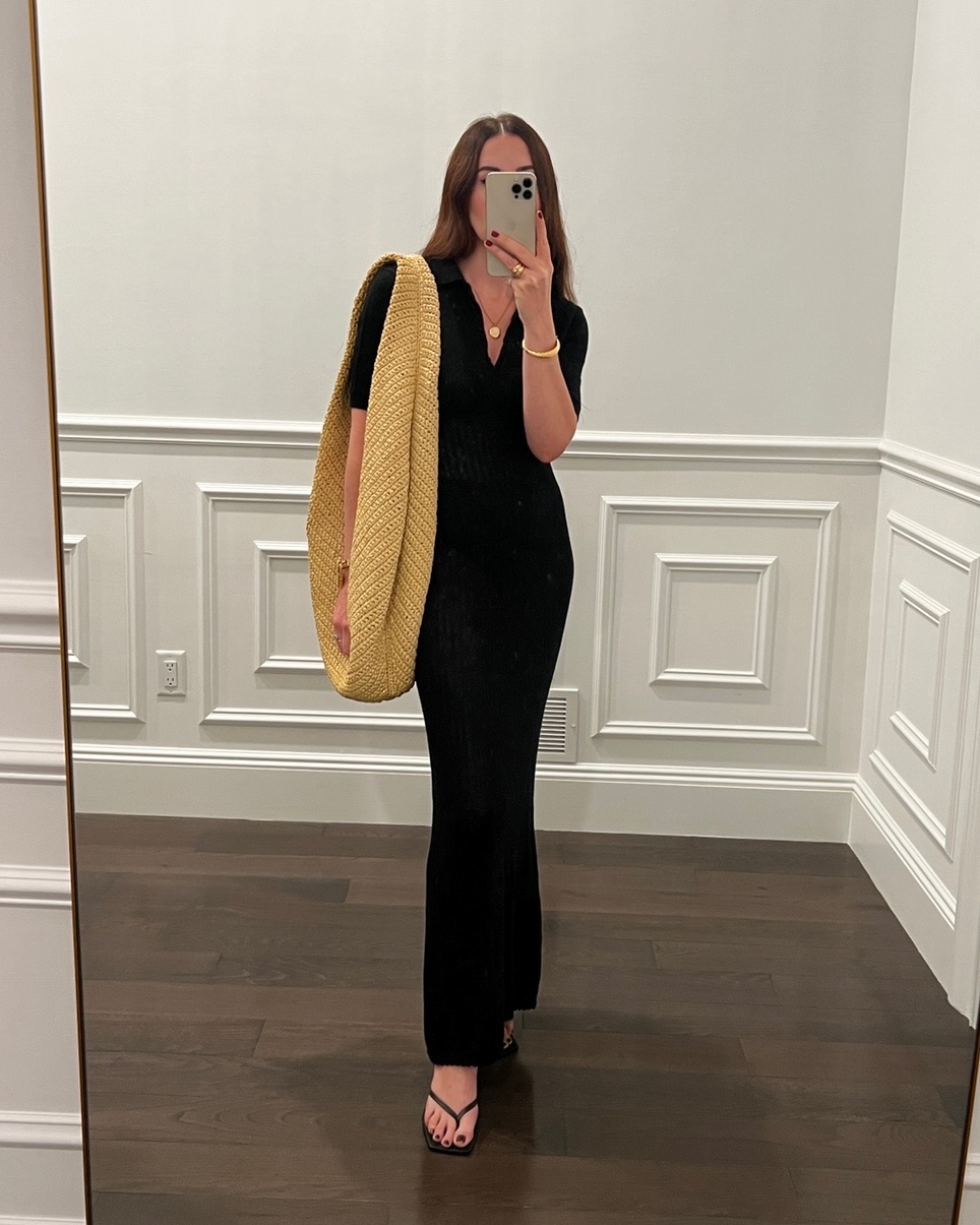 Caitlin Burke wearing a black maxi dress and carrying a Khaite woven shoulder bag.