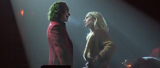 Joaquin Phoenix in Joker makeup standing with Lady Gaga as Lee Quinzel in Joker: Folie À Deux