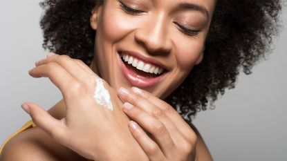 smiling woman using hand cream