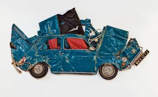 Image of a mangled blue car captured against a white background