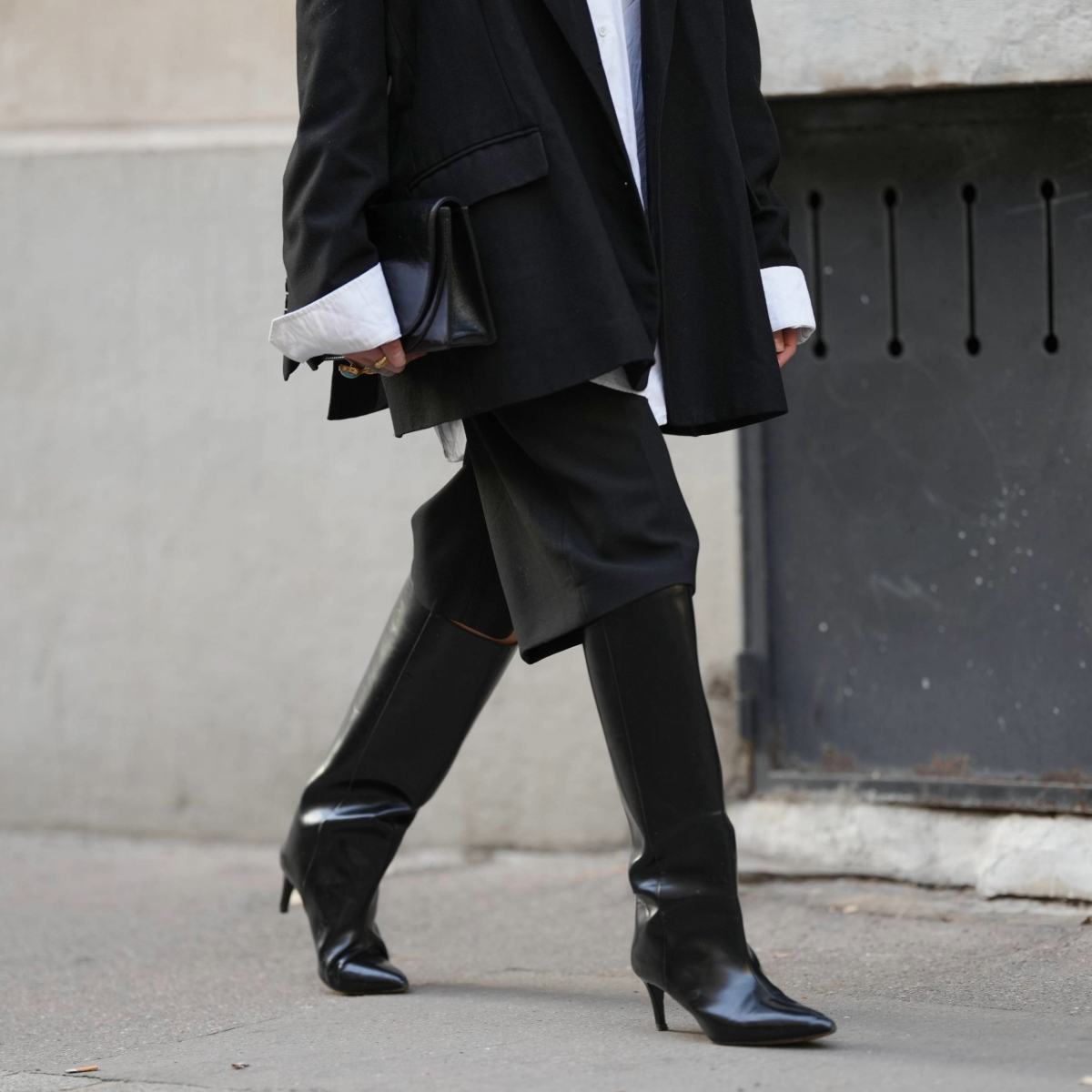 PARIS, FRANCE - NOVEMBER 05: Emy Venturini wears a black oversized blazer jacket by The Frankie Shop layered over a white cotton shirt by Louis Vuitton, black tailored knee-length shorts by Zara, black leather heeled boots by Toteme, a vintage black leather clutch bag, during a street style fashion photo session, on November 05, 2025 in Paris, France. (Photo by Edward Berthelot/Getty Images)