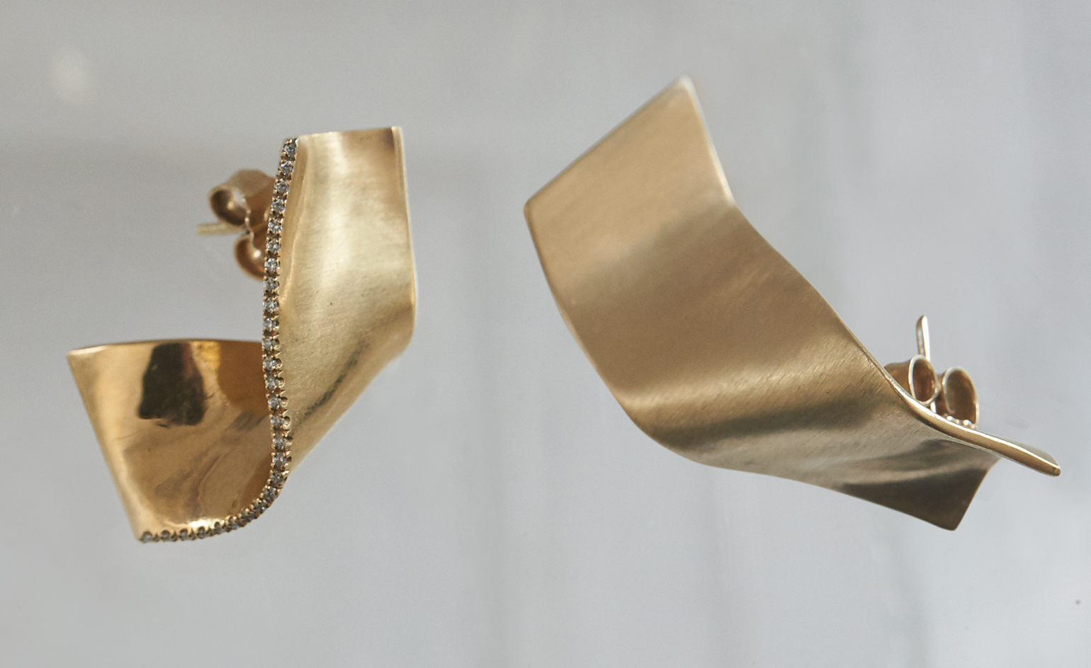 Gold pin pair of earrings photographed against a grey background