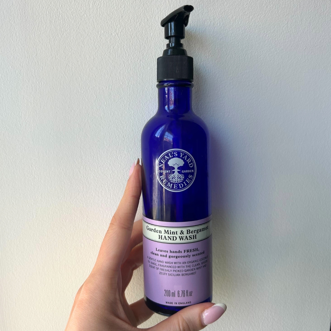 Hand holding empty bottle of Neal's Yard Garden Mint &amp;amp; Bergamot Hand Wash
