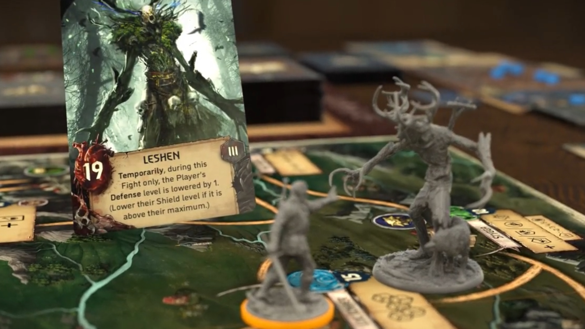 A Witcher model faces a Leshen miniature, with a Leshen card visible in the background