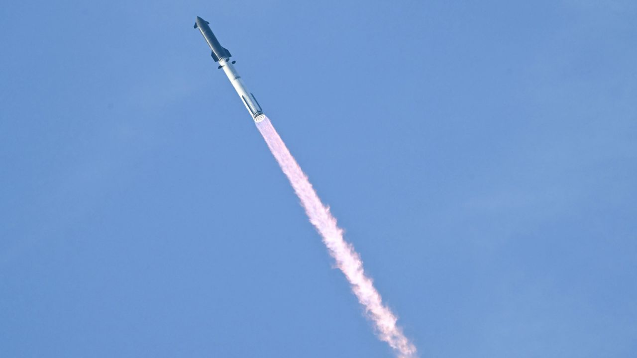 a rocket launches against a light blue sky.