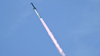 a rocket launches against a light blue sky.