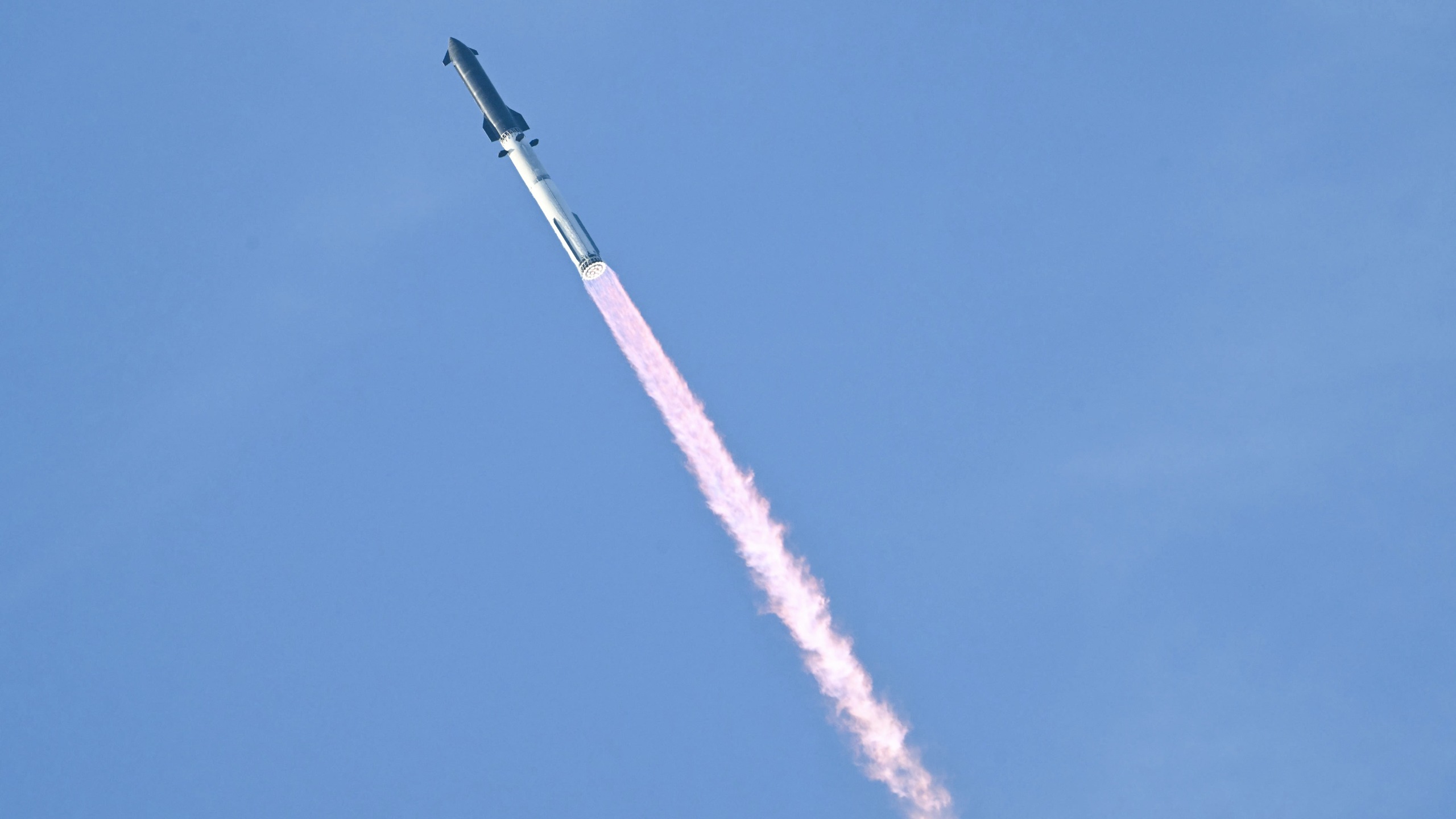 a rocket launches against a light blue sky. 