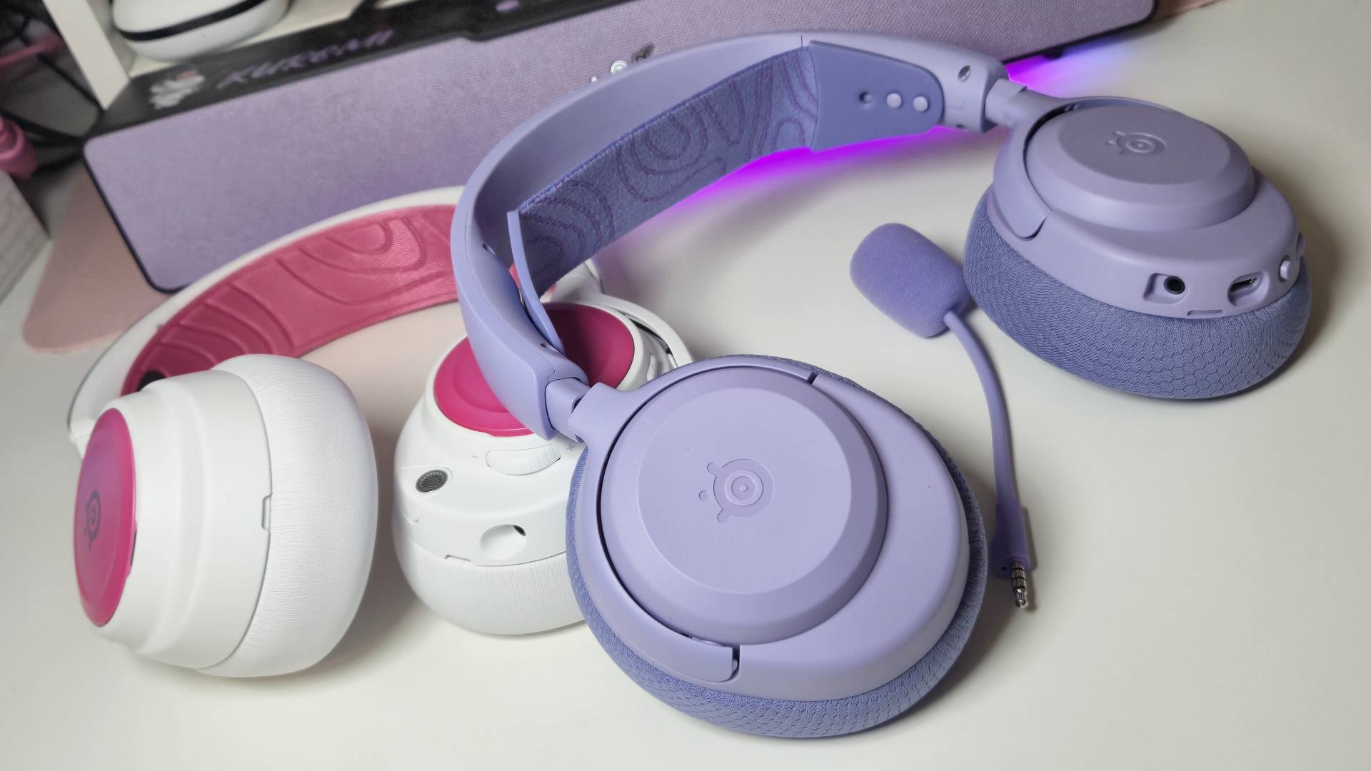 Photos of the SteelSeries Arctis Nova 3 Wireless gaming headset in Lavender, taken by writer Rosalie Newcombe, on a white desk.