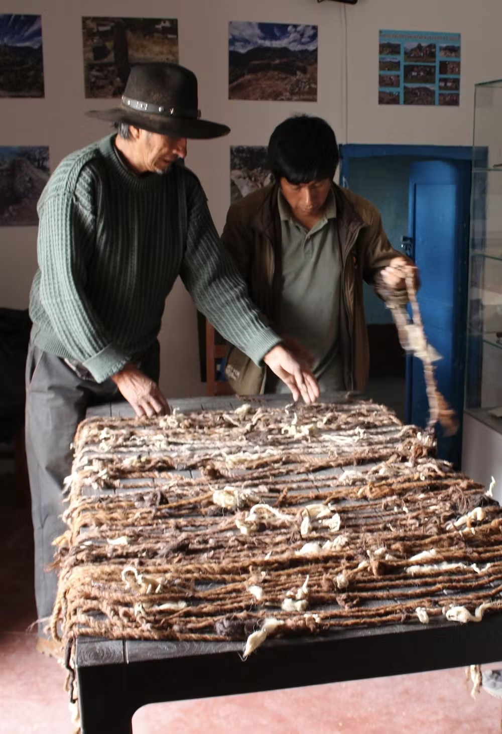Two men examine a table full of frayed, knotted strings