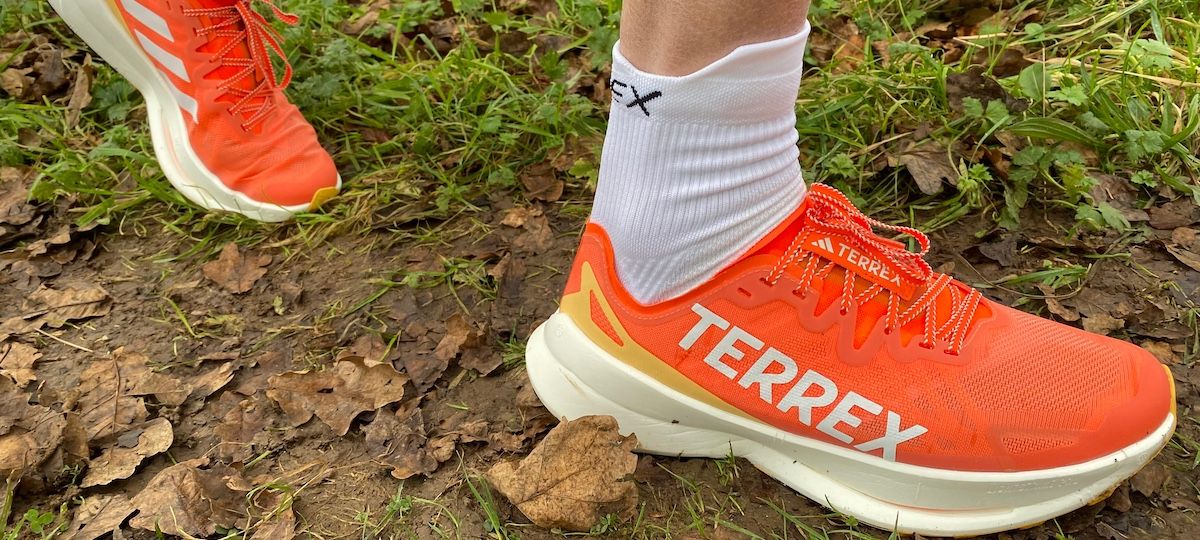 Closeup of Adidas Terrex Agravic Speed Ultra running shoes in action on muddy, leafy trail