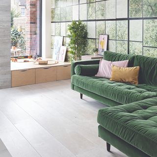 A living room with a photographic, nature-inspired wall mural and a dark green chaise velvet sofa