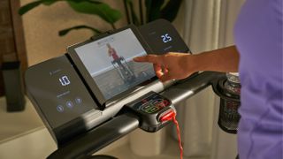 A person uses the touchscreen on the new Echelon Stride folding treadmill