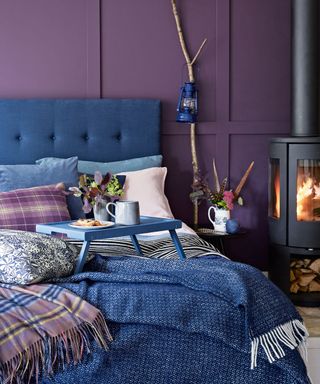bedroom with purple wall and blue serving bed tray and fireplace