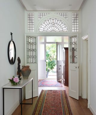 large entryway with latticed glass around the door, a console table and a runner