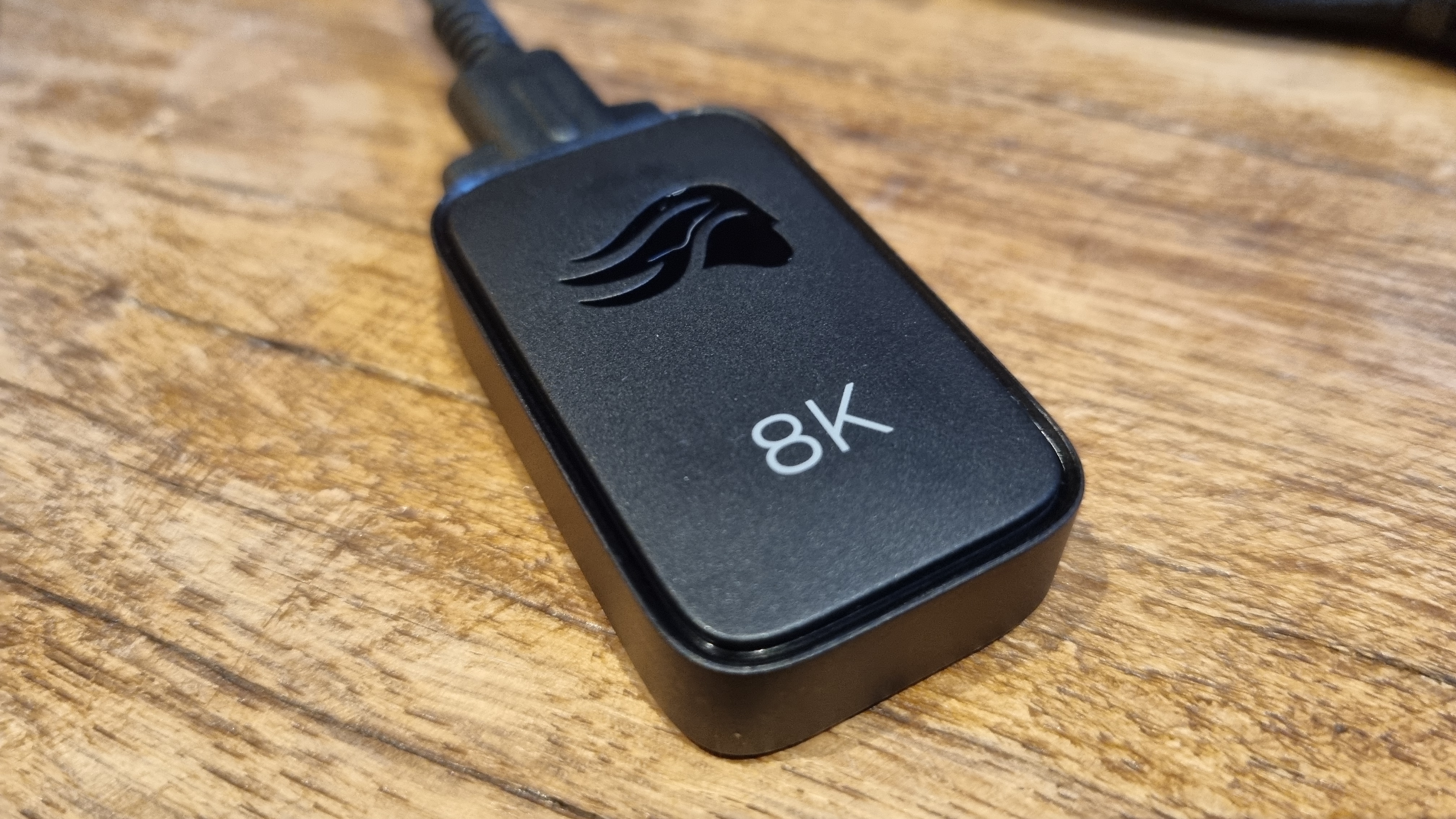 The 8K dongle included with the Glorious Series 2 Pro wireless gaming mouse, on a wooden surface.