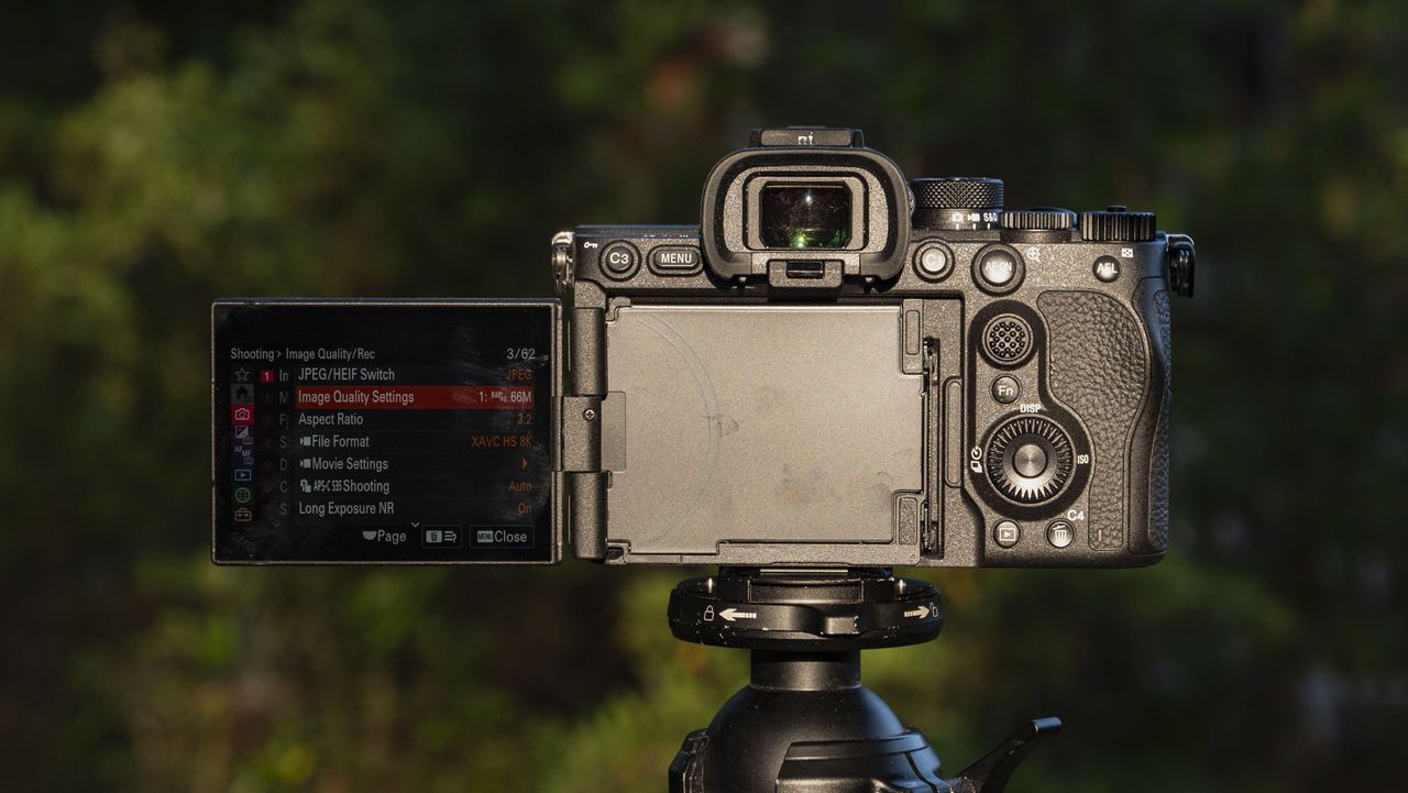 Rear of the Sony A7R VI camera with screen flipped out to the side, it's mounted to a tripod outdoors, there's a natural background