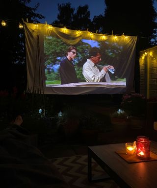 film projected onto a portable screen in a garden