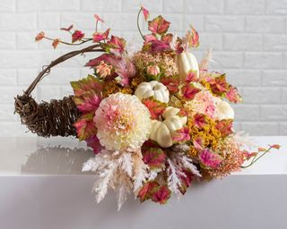 Pumpkin and mixed floral arrangement in Cornucopia on outdoor dining table