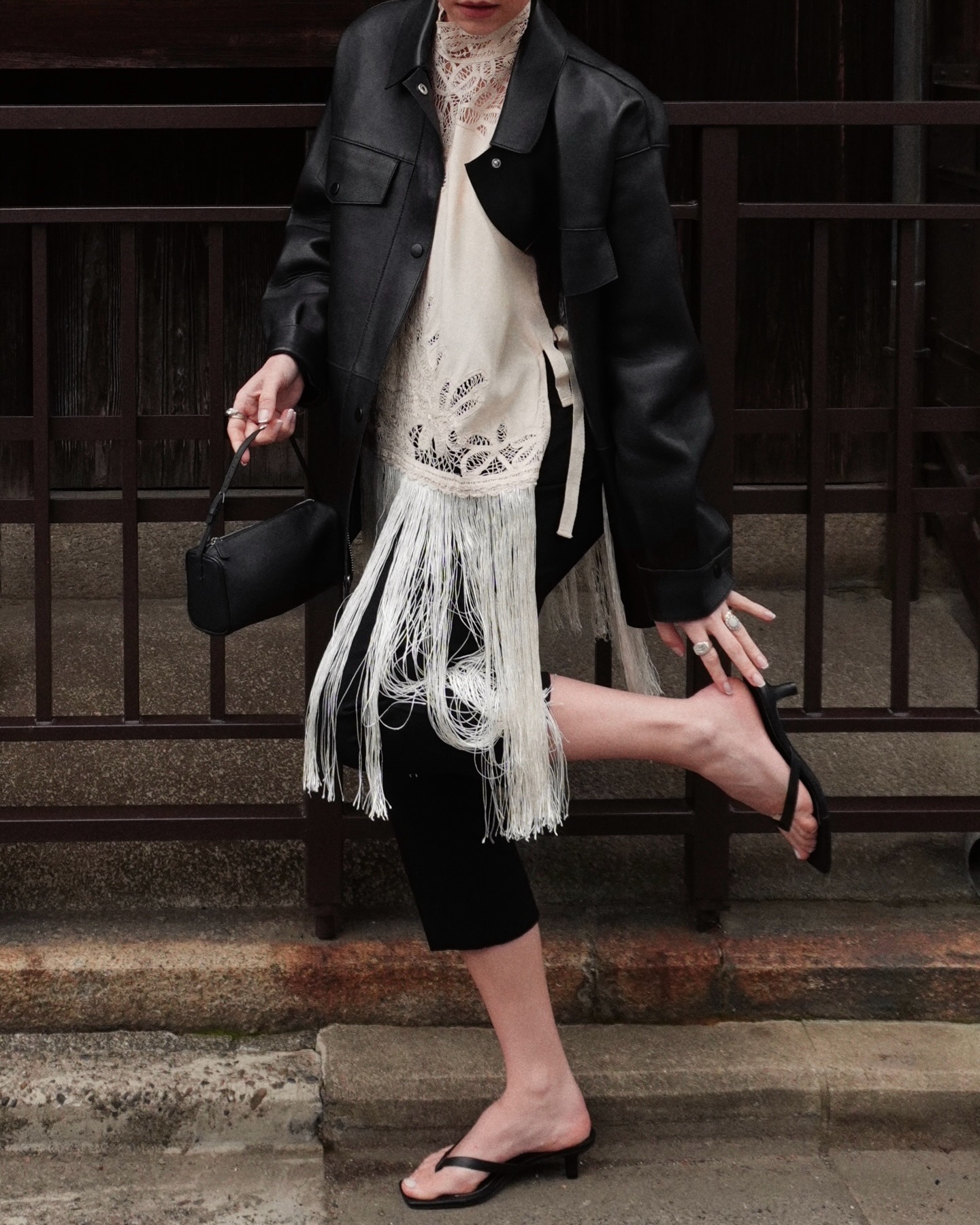 thealiceedit wears a hybrid summer shoe trend. She wears black thong sandals, black capris a fringe top and black leather jacket.