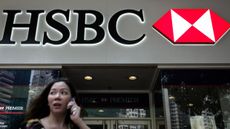 A woman talks on the phone near a branch of HSBC bank