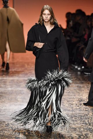 A photo of a model stomping the runway in a feathered skirt from Bottega Veneta's fall 2024 collection