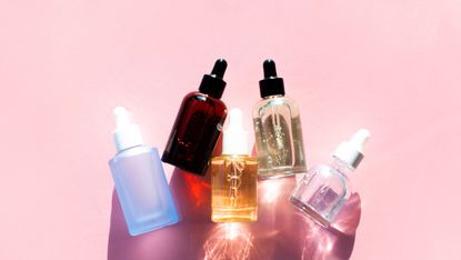 Top view of bottles of moisturizing cosmetic products arranged in line on pink background, hyaluronic acid for hair