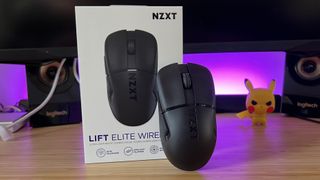 NZXT Lift Elite Wireless gaming mouse leaning against packaging on a wooden desk with purple RGB lighting