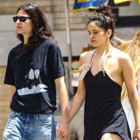 Rosalia wears a black mini dress with two feathers adorned to its straps and pointed-toe mules while holding hands with model Loli Bahia on a date in Manhattan