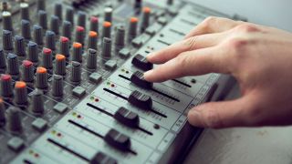 Close up of hand adjusting sound mixing board