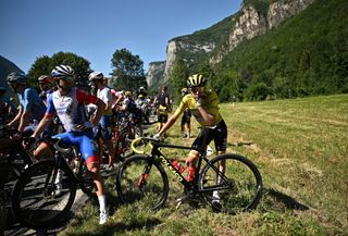 Riders including race leader Tadej Pogačar wait for the protesters to be cleared from the route of stage 10 of the Tour de France 2022