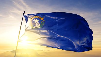 Nevada state flag blowing in the wind at sunrise for Nevada state tax story
