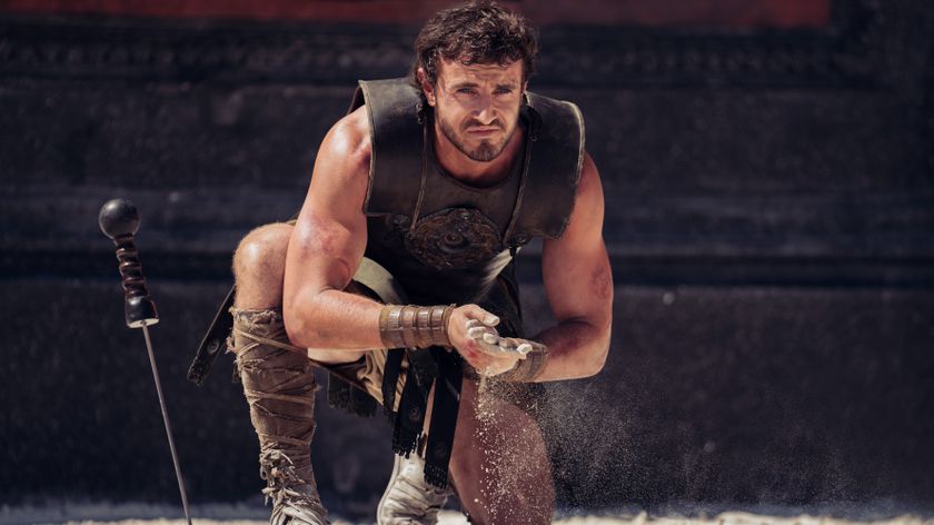 A still from Paramount Pictures&#039; Gladiator 2 with Paul Mescal kneeling in an arena with sand running through his fingers.